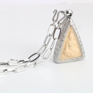 Close-up of silver Buddhist amulet pendant with ornate engraving and thick O-chain necklace