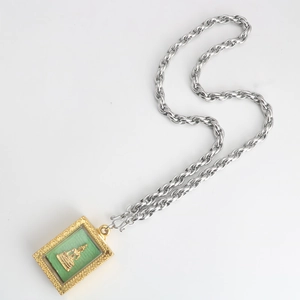 Détail d'un pendentif amulette thaïlandaise avec relief vert et chaîne torsadée argentée