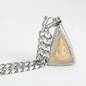 Detail of Thai silver Buddha pendant with intricate floral frame and heavy metal chain