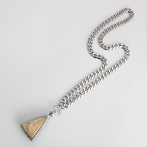 Close-up of a silver stainless steel curb chain with a Buddhist relief pendant