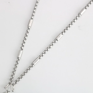 Detail of stainless steel box chain necklace featuring cylinder accents and S-hook clasp