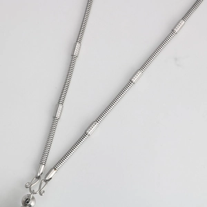 Detail of stainless steel snake chain necklace with decorative beads and S-hook clasp
