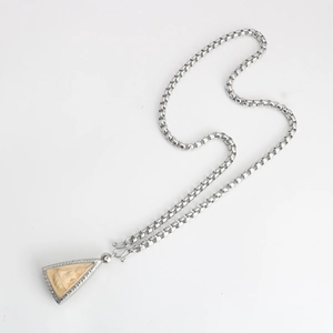 Macro detail of a silver square link chain and religious relief pendant with engraving