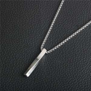 Macro shot of silver twisted column pendant with box chain on black leather background