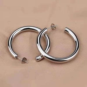 Boucles d'oreilles créoles C en acier inoxydable argenté sur tissu satiné rose