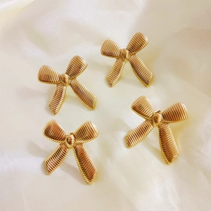 Gouden titanium stalen strik oorbellen met textuur op elegante beige zijden achtergrond