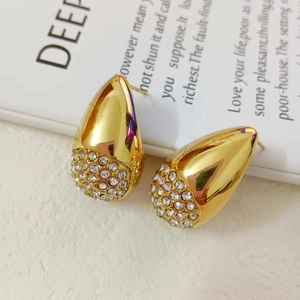 Detailed close-up of water drop earrings in gold finish with sparkling clear rhinestones