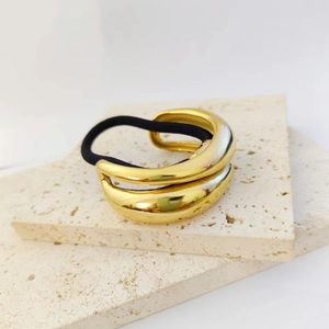 Close-up of golden irregular double-layered curved hair cuff with black elastic tie