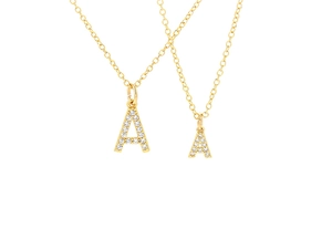 Macro shot of gold letter A pendants with white zircon stones and delicate cable chain