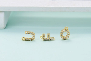 Detail view of gold-plated U, L, O letter pendants with white cubic zirconia stones