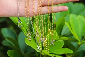 Macro shot of silver and gold plated initial necklaces with sparkling pavé zircons