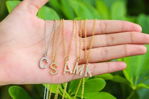 Detailed view of gold and silver initial pendants with sparkling micro-pave zircons