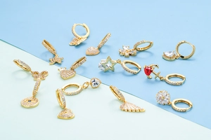Macro di vari orecchini huggie placcati in oro con ciondoli a cuore, stella e farfalla