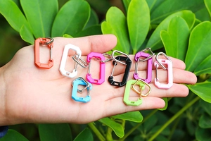Detailed view of colorful mini carabiner keychains in various vibrant colors held in hand