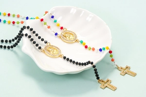 Detail of colorful beads and gold-plated rosary necklaces with a crystal cross on a shell plate