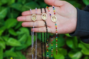 Detailed view of colorful religious rosary necklaces with golden Virgin Mary and cross