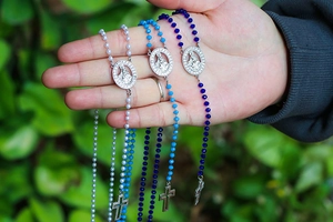 Close-up of Virgin Mary rosary necklaces with colorful beads and metal cross charms
