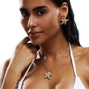 Golden starfish jewelry set with sparkling crystals on a model with water droplets