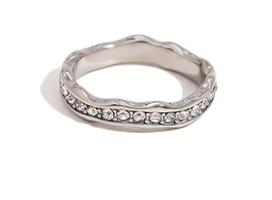 Makroansicht des wellenförmigen Edelstahlrings mit glitzernden Mikropavé-Diamanten