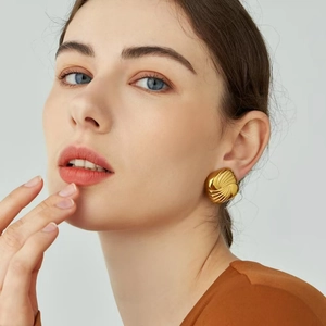 Macro view of vintage style gold-plated earrings with shell-like textured surface