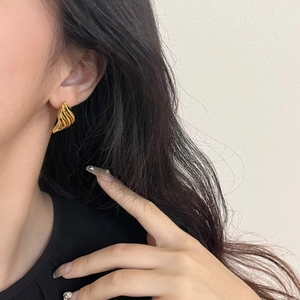 Close-up of vintage scalloped gold earrings with textured shell finish on model
