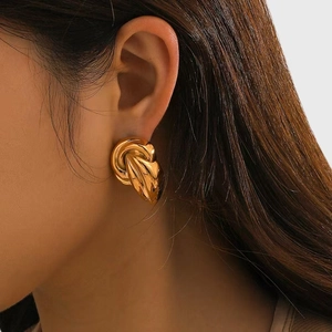 Macro view of gold-plated twisted knot earrings on model for a vintage luxury look