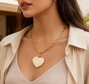 Close-up of a vintage 18K gold stainless steel necklace with a marbled resin heart pendant