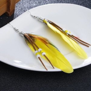 Detailed close-up of yellow bohemian feather earrings with beads and leather cords