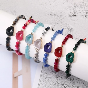 Detail van zeven kleurrijke hars geode bedeltjes met koperen randen op kralenarmbanden