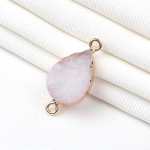 Primer plano de un conector de gota en piedra druzy rosa claro con engaste de oro rosa