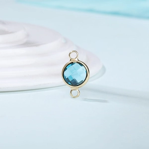 Close-up of a sky blue birthstone charm with golden double loops for DIY jewelry