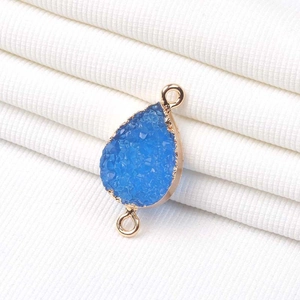 Detalle de colgante de cristal druzy azul con bordes dorados y bucles dobles para DIY