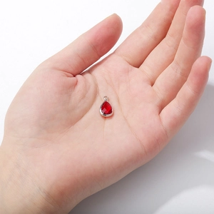 Detailed view of a red teardrop faceted glass crystal pendant with silver metal base