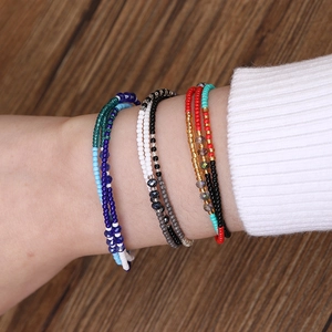 Bracelet multi-rangs bohème en perles pour femme porté au poignet sur fond chaleureux