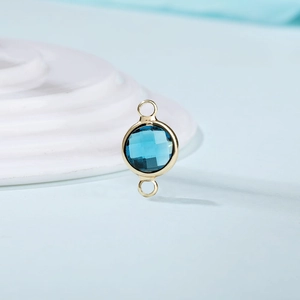 Detail of faceted blue crystal birthstone pendant with gold double bail connectors