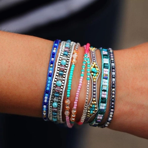 Gros plan de bracelets bohèmes multicouches en perles colorées sur un poignet féminin
