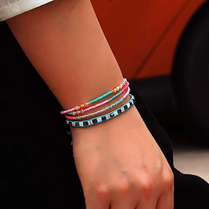Détail d'un ensemble de quatre bracelets bohèmes faits main en perles colorées sur un poignet