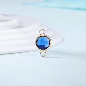 Detailed view of dark blue round faceted crystal birthstone charm with gold metal frame