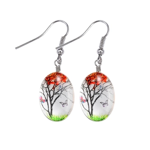 Detailed view of silver hook earrings with bohemian glass tree and butterfly art