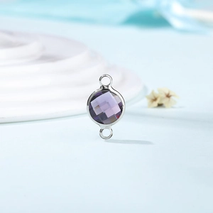 Macro view of purple faceted crystal charm with silver metal frame and double loops