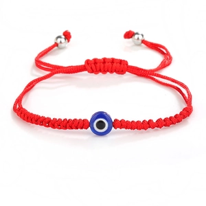 Detalle de pulsera de hilo rojo trenzado con ojo turco azul y cierre ajustable