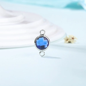 Detail of a dark blue birthstone crystal connector with silver dual-hole metal frame