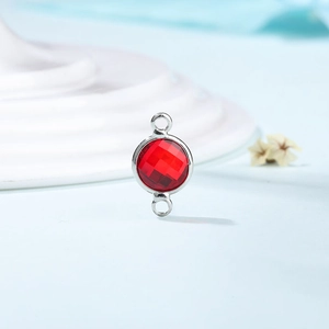 Macro view of a red crystal birthstone connector with dual loops for DIY jewelry
