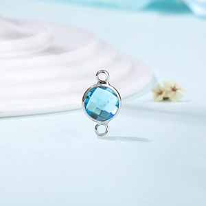 Detailed view of light blue faceted birthstone pendant with silver metal connector rings