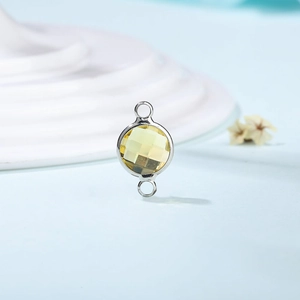 Macro shot of circular dual-hole silver connector with yellow faceted crystal stone