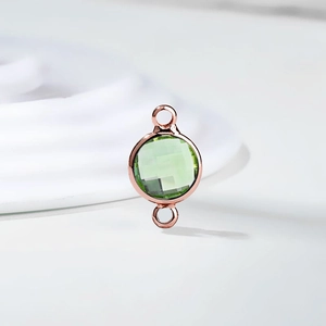 Close-up of a double-loop round light green crystal charm in rose gold plating for DIY jewelry