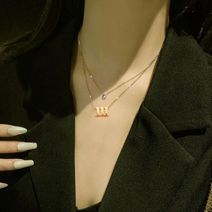 Close-up of double layer gold necklace with cursive M pendant and sparkling zircon stone