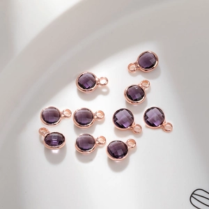 Close-up of faceted purple glass birthstone charms with rose gold copper plating for DIY