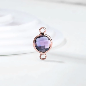 Close-up of faceted purple crystal pendant with rose gold casing and dual loops