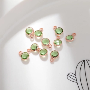 Macro shot of 6mm green faceted birthstone pendants in rose gold plated metal settings